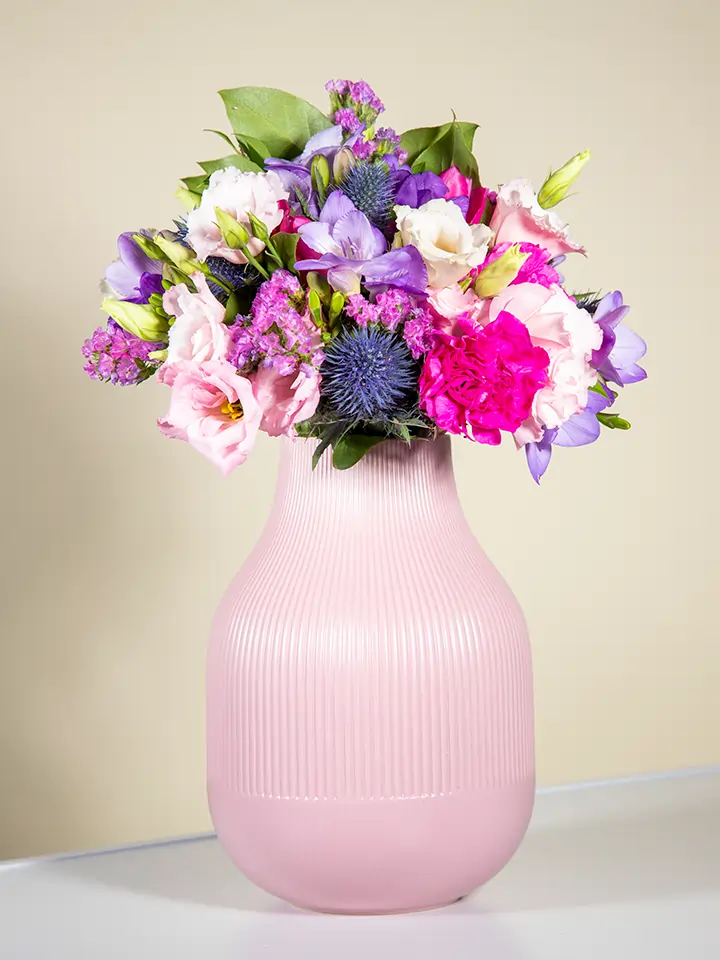 Bouquet viola lilla con lisianthus eryngium garofani in vaso rosa